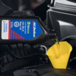 Chevy service technician putting oil into a vehicle